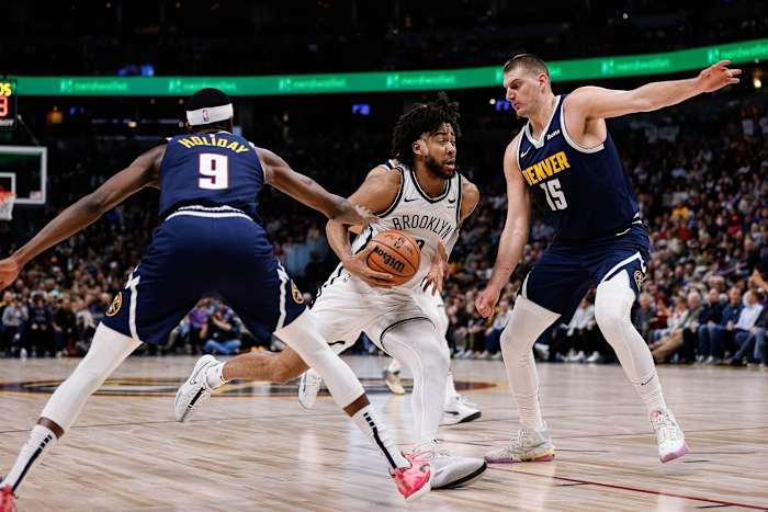 Brooklyn Nets forward Trendon Watford (9) drives to the net against Denver Nuggets forward Justin Holiday (9) and center Nikola Jokic (15)